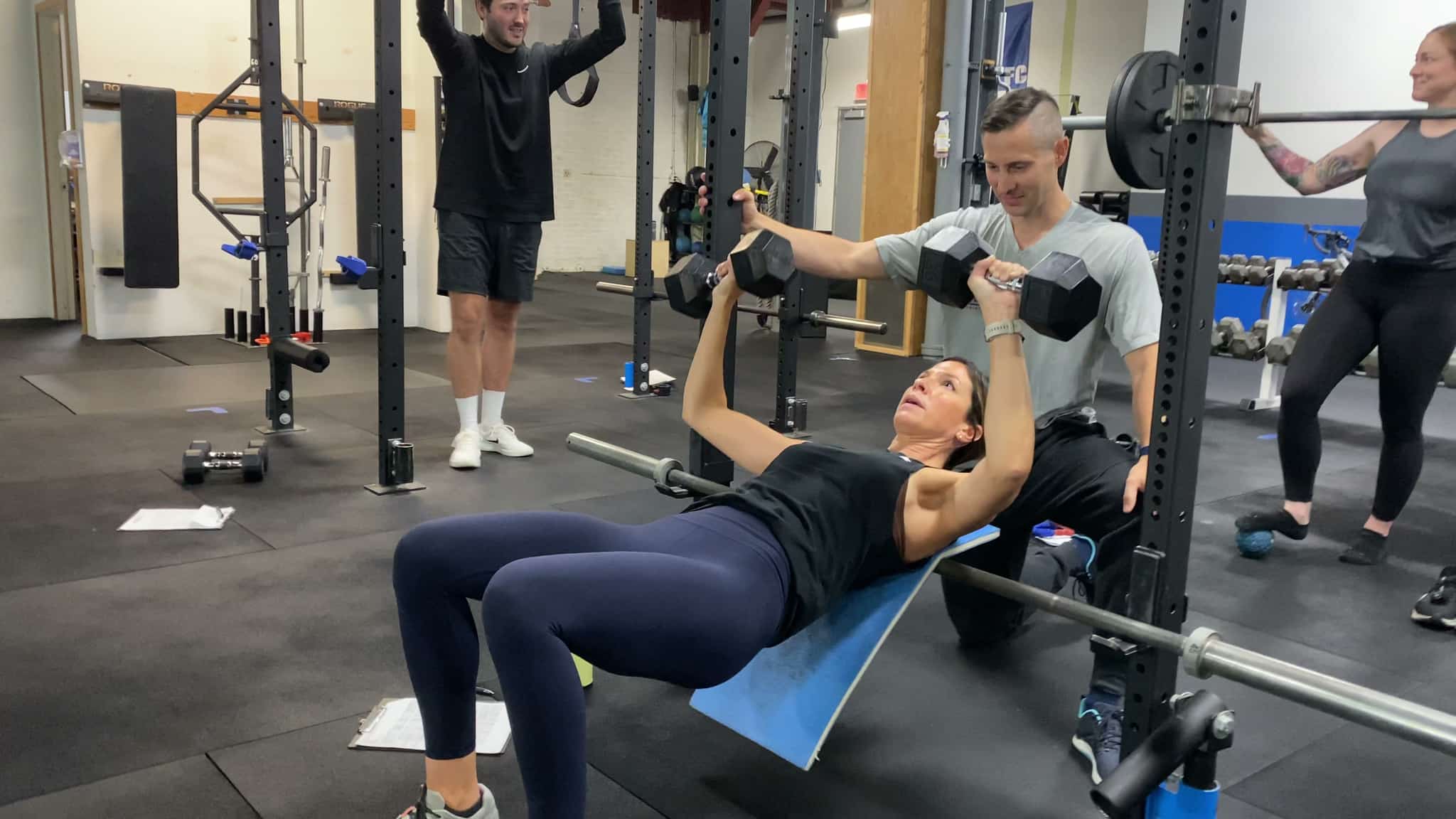 The training floor at Peak Condition: a coach alongside an athlete mid-set, with others training around them